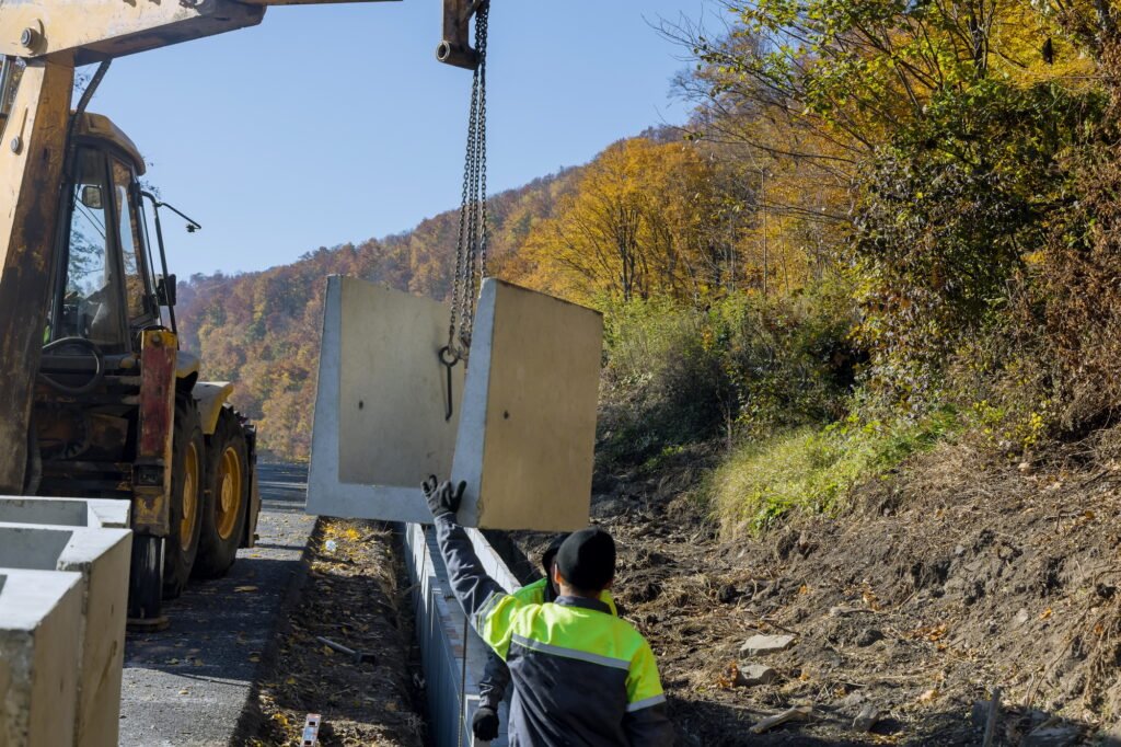 Concrete drain construction workers installing precast square U-shape