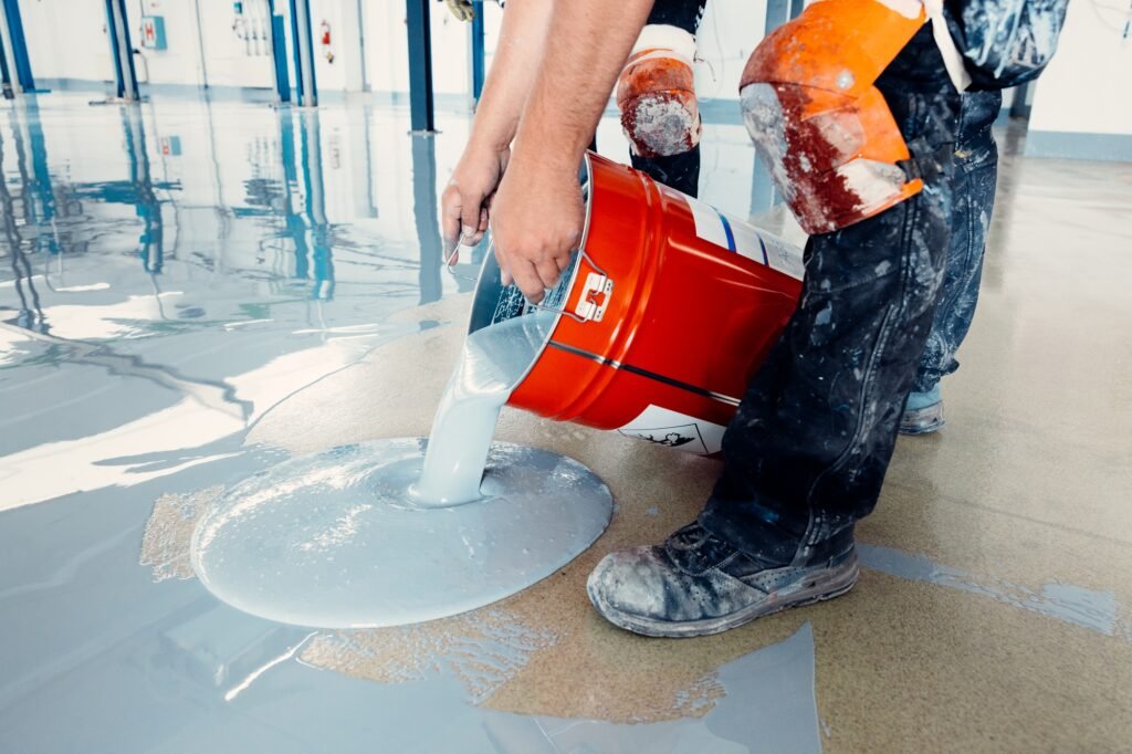 Construction workers pouring epoxy resin on concrete floor
