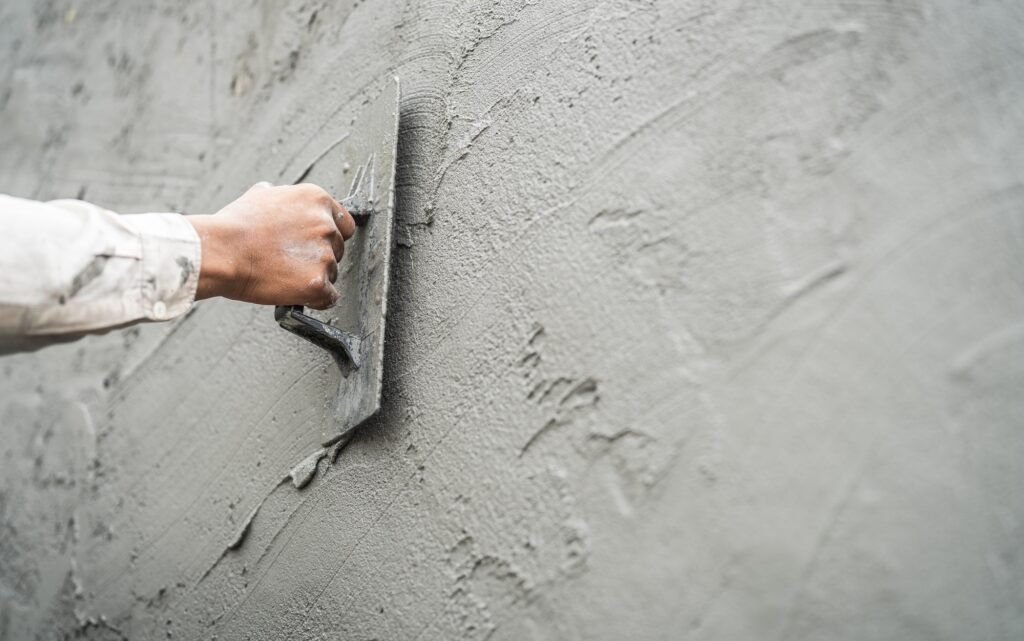 Hand worker plastering cement wall with rough concrete for smooth building wall well free space